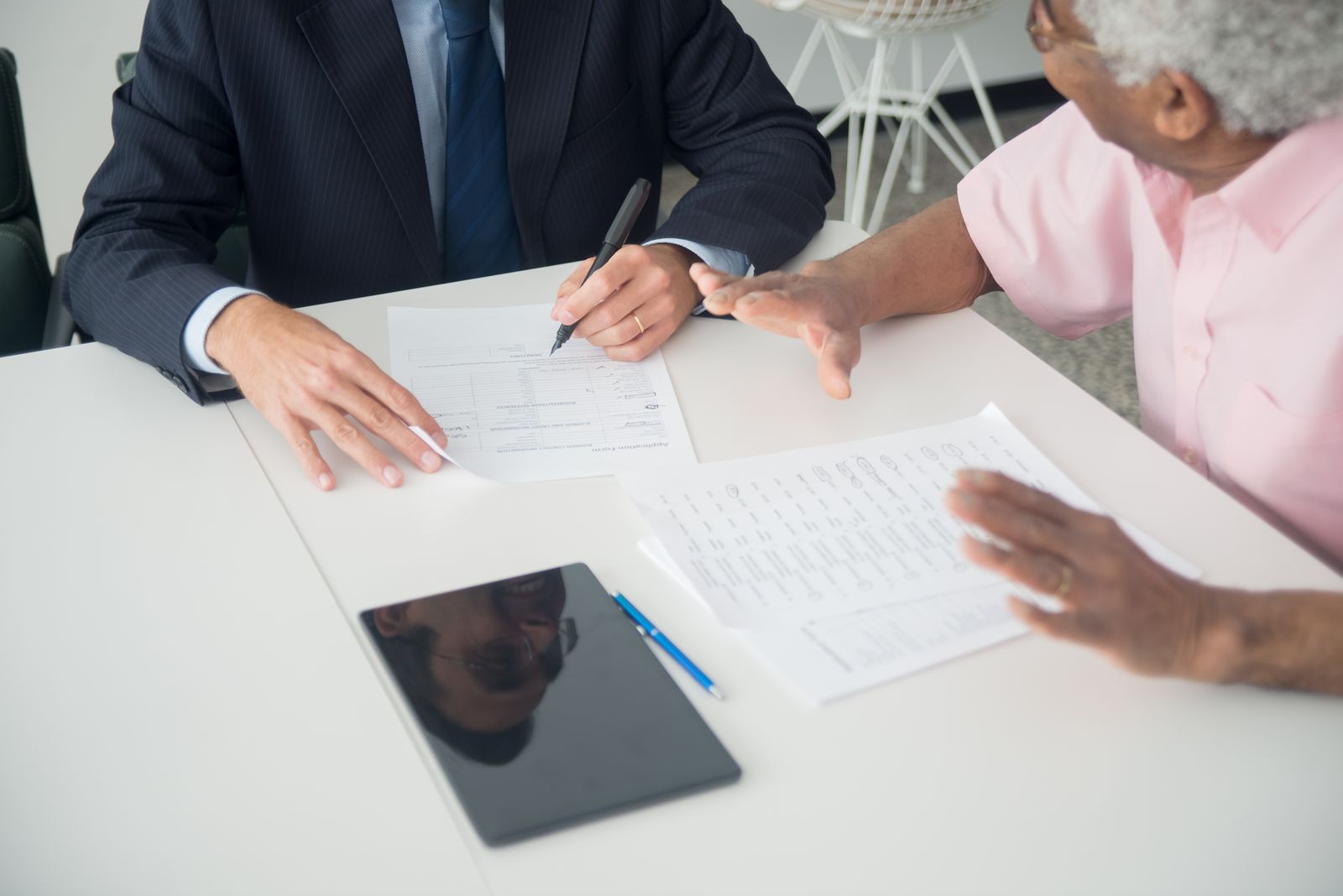 An advisor and an older client reviewing documents at a table